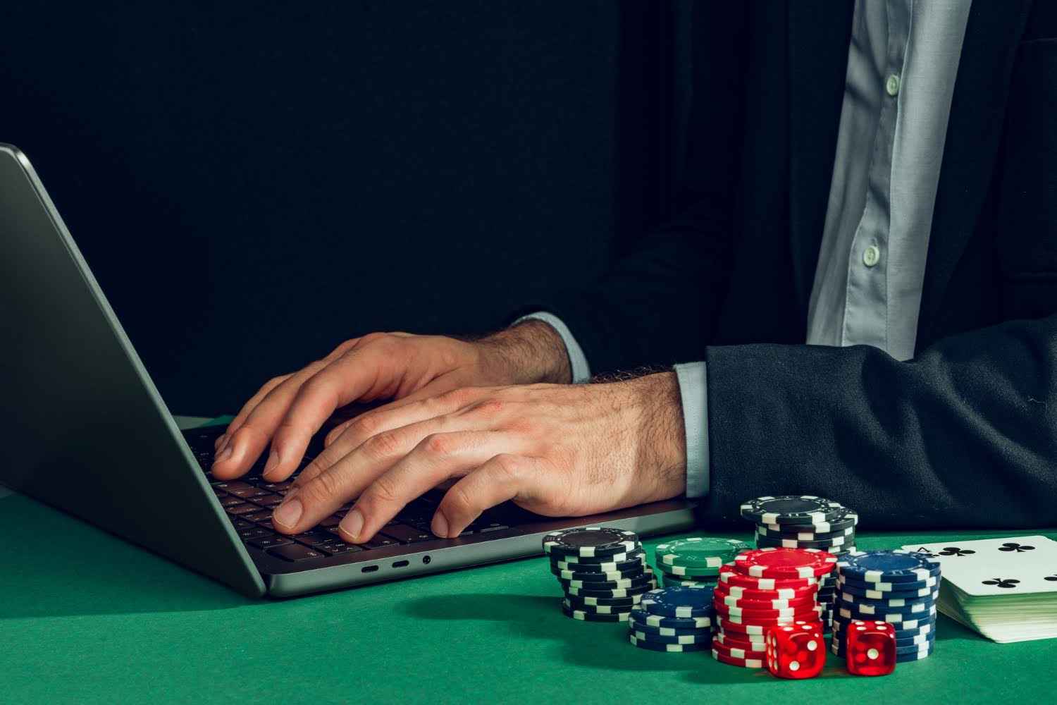 Alt: Hands typing on laptop at a green felt gaming table